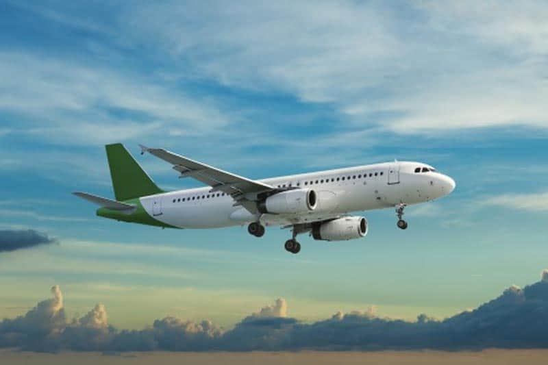 image of an airplane with a green tail flying through the sky