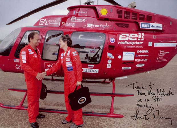 signed image of a woman and man shaking hands in front of a red helicopter