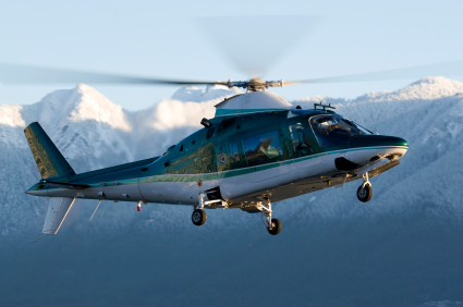Bell 429 helicopter flying next to mountains